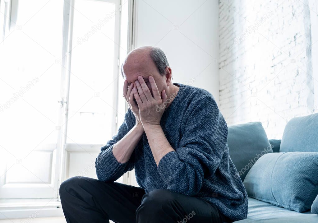 Senior old man feeling desperate sad looking worried depressed thoughtful and lonely on couch at home in Aging Mental health Personal problems and Life style concept.