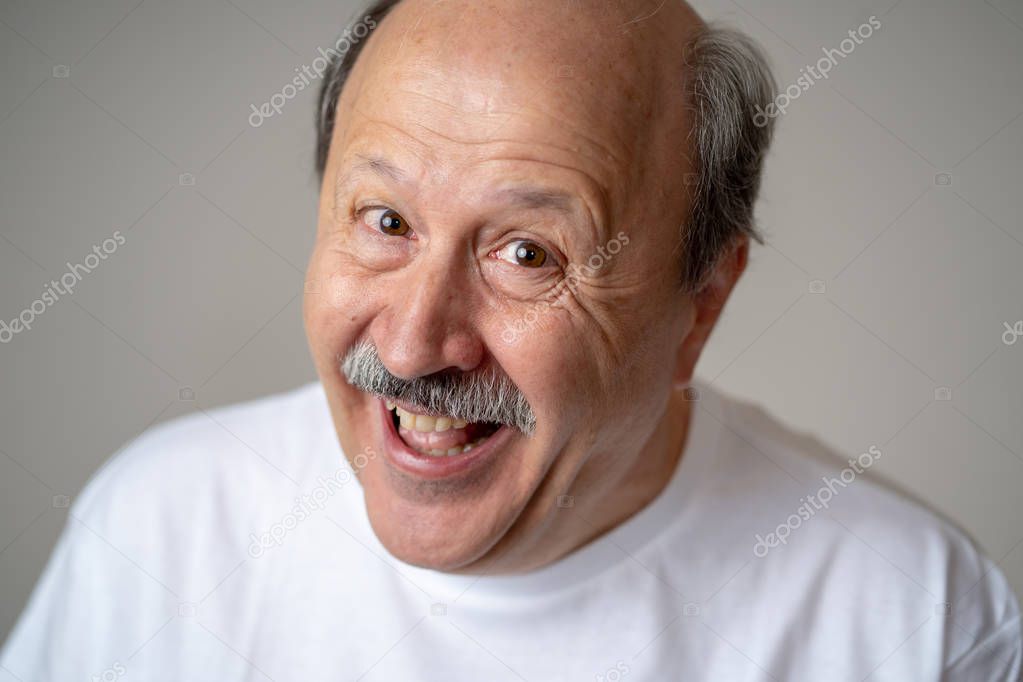 Smiling and laughing 60s year old senior man candid close up portrait in human emotions and facial expressions concept isolated in neutral background.