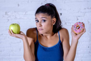 Güzel genç kadın sağlıklı sağlıksız gıda, elma ve halka arasında seçim yapmak zorunda şüphe detoks yeme, kalori ve diyet kavramı.