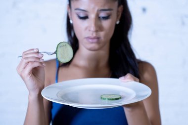 Portrait o f young attractive woman feeling sad and bored with diet not wanting to eat vegetables or healthy food in Dieting Eating Disorders and weight loss concept. clipart