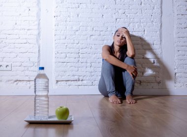 Umutsuz diyet genç kadın deli diyet irade ve beslenme sembolü olarak bir elma meyve ve su üzgün seyir yerde oturuyordu bozukluğu.