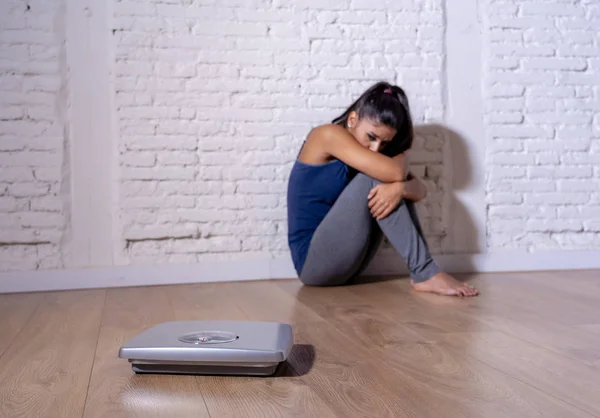 年轻的厌食症少女坐在地面上看规模焦虑和抑郁在节食和饮食紊乱概念 — 图库照片