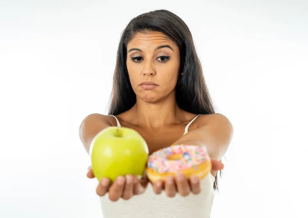 美丽的年轻女子诱惑不得不在健康不健康的食物 排毒饮食 卡路里和饮食概念的苹果和甜甜圈之间做出选择 — 图库照片