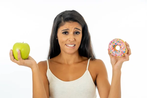 美丽的年轻女子诱惑不得不在健康不健康的食物 排毒饮食 卡路里和饮食概念的苹果和甜甜圈之间做出选择 — 图库照片