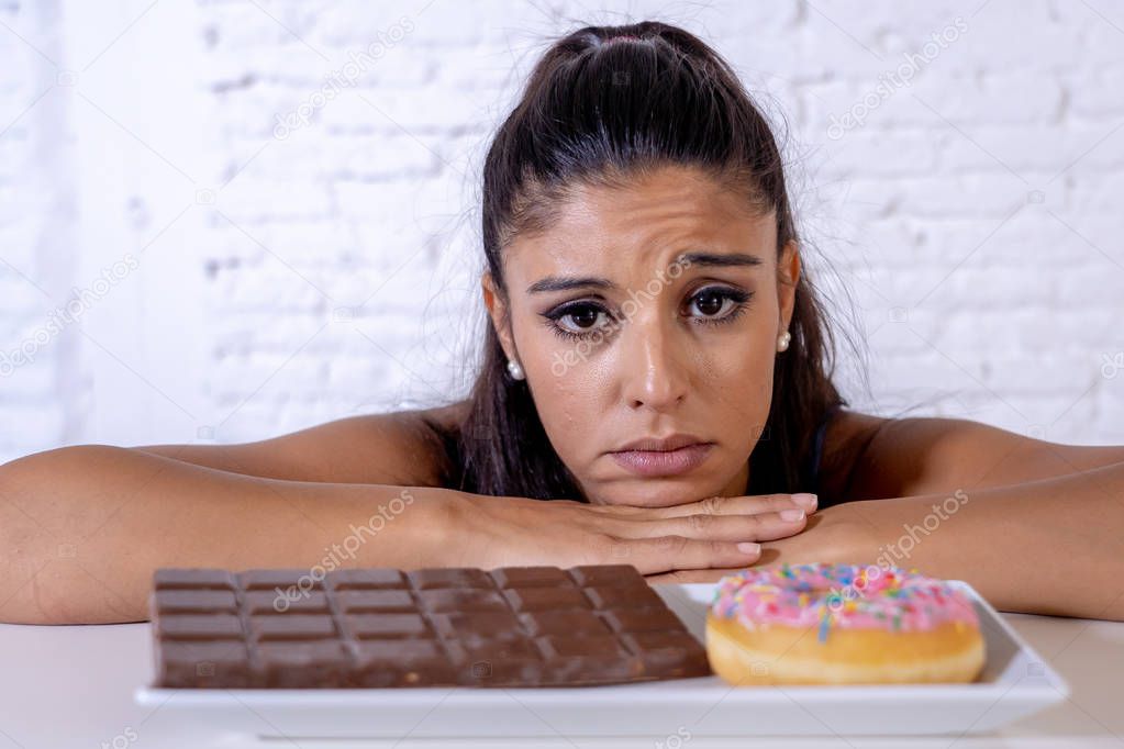 Hungry beautiful young woman unhappy craving sweet chocolate and doughnuts and cannot eat in Dieting Weight loss Sugar addiction Diabetic and unhealthy healthy food concept.