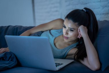 Çalışma ve internet bağımlılığı ve aşırı iş yükü kavram gece geç saatlerde bilgisayar evde kanepede ile internette sörf yorgun çekici genç kadın.