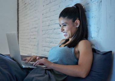 Sohbet ve evde yatakta yatarken internette arama neşeli güzel genç latin kadın duygu mutlu ve şanslı iletişim sosyal medya internet bağımlılığı kavramı.