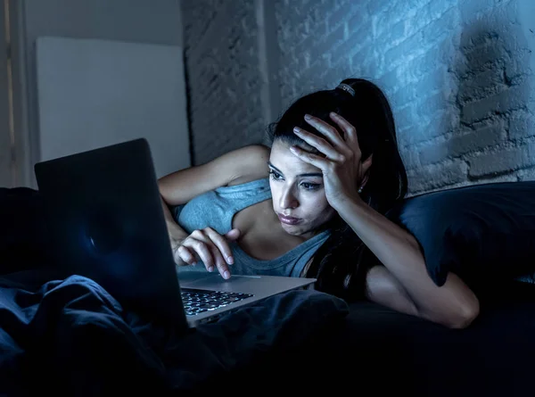 疲惫的有吸引力的年轻妇女在互联网上工作和上网与电脑在沙发上深夜在互联网成瘾和加班的概念 — 图库照片