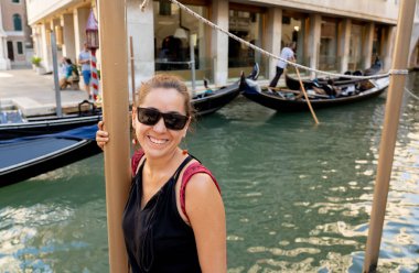 Poz ve yaz tatil seyahat Venedik kanalda Europe kavramı etrafında, güneş gözlüklü kameraya bakarak çekici doğal latin turist kadın.