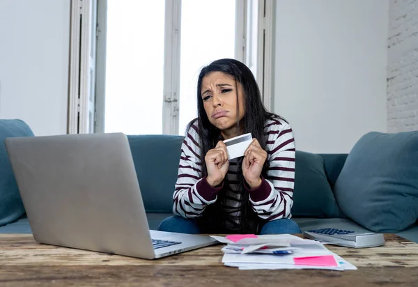 魅力的な若いラテン女性は絶望的なクレジット カードとラップトップやまクレジット カード問題債務オンライン決済オンライン ショッピング オンライン バンキング悪い財政状況で家のソファの上で猛烈です — ストック写真