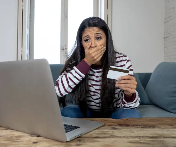 有吸引力的年轻拉丁女人绝望和愤怒与信用卡和笔记本电脑选址在沙发首页信用卡问题债务在线支付网上购物网上银行糟糕的财务状况 — 图库照片