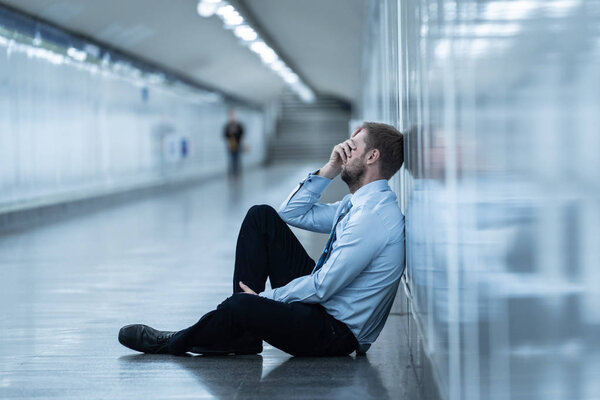 Young jobless business man suffering depression sitting on ground street underground leaning on wall alone looking desperate in Emotional pain Mental health Unemployment and Human emotions concept.