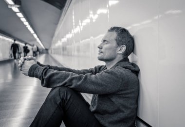 Sefil işsiz genç adam ağlayan uyuşturucu bağımlısı evsizlere depresyon stres zemin sokak Metro'ya ruhsal bozukluk duygusal acı üzüntü yalnız duvara yaslanmış umutsuz seyir üzerinde oturan.