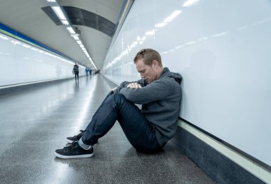 Sefil işsiz genç adam ağlayan uyuşturucu bağımlısı evsizlere depresyon stres zemin sokak Metro'ya ruhsal bozukluk duygusal acı üzüntü yalnız duvara yaslanmış umutsuz seyir üzerinde oturan.