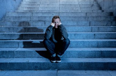 Lost ın depresyon zemin beton merdiven duygusal acı yalnızlık üzüntü zihinsel sağlık kavramı grunge aydınlatmada yalnız oturan genç umutsuz işsiz adam rahat kıyafetler içinde terk.