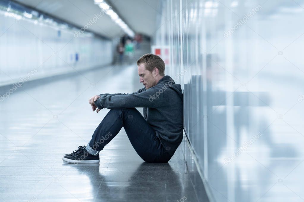 Miserable jobless young man crying Drug addict Homeless in depression stress sitting on ground street subway tunnel looking desperate leaning on wall alone in Mental disorder Emotional pain Sadness.