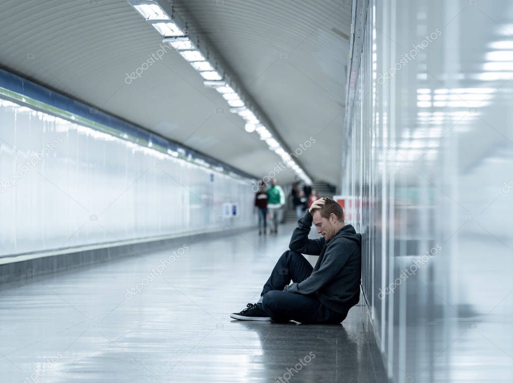Miserable jobless young man crying Drug addict Homeless in depression stress sitting on ground street subway tunnel looking desperate leaning on wall alone in Mental disorder Emotional pain Sadness.