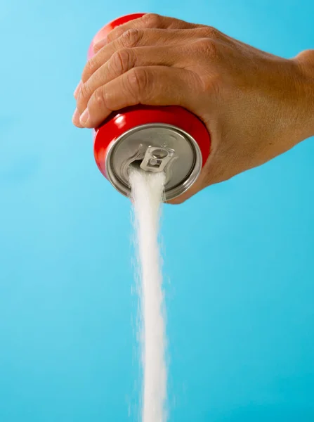 Hand holding soda can pouring crazy amount of sugar in metaphor of sugar content of refreshing drink isolated on red background in Nutrition Diet Unhealthy food Addiction and Excess calories content.