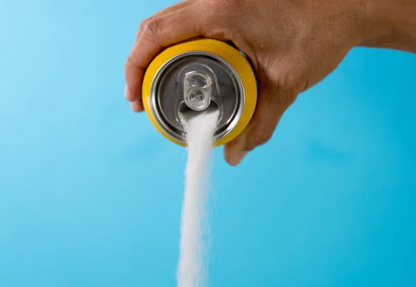 Hand holding soda can pouring crazy amount of sugar in metaphor of sugar content of refreshing drink isolated on red background in Nutrition Diet Unhealthy food Addiction and Excess calories content.