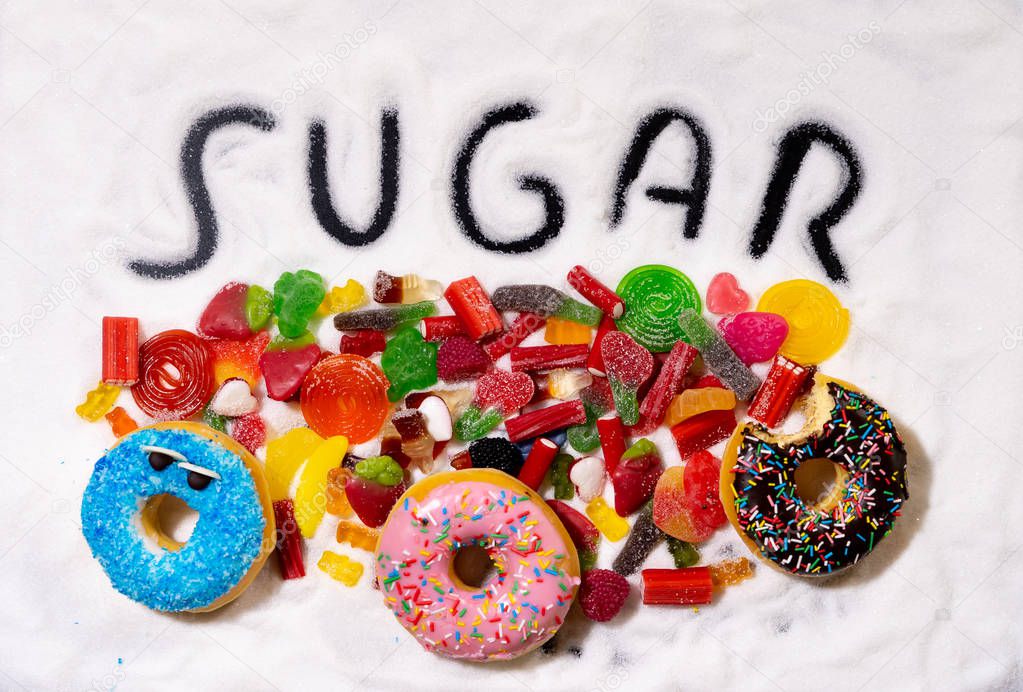 Colorful selection of different child sweets candies and treats with sugar written metaphor of too much sugar causes Health problems Nutrition Obesity Diabetes Dental care and Sugar addiction.