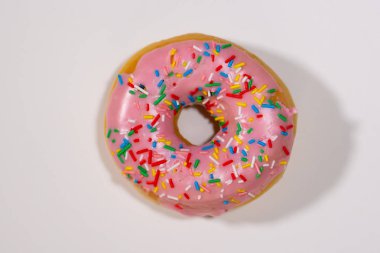 Sevimli beyaz bir arka plan üzerinde izole lezzetli şeker sırlı pembe çörek fotoğraf stüdyo yakın çekim resmin sağlıksız gıda ve şeker bağımlılığı davranır.