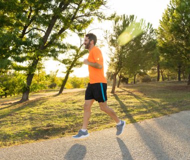 Spor giyim dışında maraton için eğitim Park'ta spor sağlıklı yaşam tarzı ve koşu çapraz ülke eğitim egzersiz açık havada kavramı güzel yaz gününde günbatımında çalışan mutlu runner.