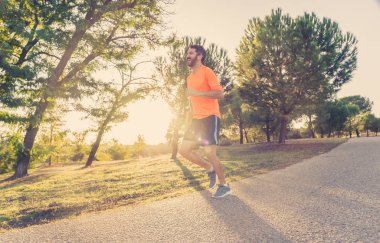 Spor giyim dışında maraton için eğitim Park'ta spor sağlıklı yaşam tarzı ve koşu çapraz ülke eğitim egzersiz açık havada kavramı güzel yaz gününde günbatımında çalışan mutlu runner.