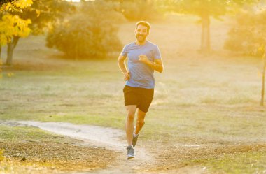 Spor giyim dışında maraton için eğitim Park'ta spor sağlıklı yaşam tarzı ve koşu çapraz ülke eğitim egzersiz açık havada kavramı güzel yaz gününde günbatımında çalışan mutlu runner.