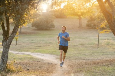 Spor giyim dışında maraton için eğitim Park'ta spor sağlıklı yaşam tarzı ve koşu çapraz ülke eğitim egzersiz açık havada kavramı güzel yaz gününde günbatımında çalışan mutlu runner.
