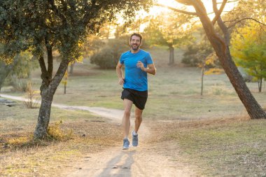 Spor giyim dışında maraton için eğitim Park'ta spor sağlıklı yaşam tarzı ve koşu çapraz ülke eğitim egzersiz açık havada kavramı güzel yaz gününde günbatımında çalışan mutlu runner.