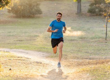Spor giyim dışında maraton için eğitim Park'ta spor sağlıklı yaşam tarzı ve koşu çapraz ülke eğitim egzersiz açık havada kavramı güzel yaz gününde günbatımında çalışan mutlu runner.