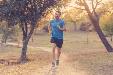 Spor giyim dışında maraton için eğitim Park'ta spor sağlıklı yaşam tarzı ve koşu çapraz ülke eğitim egzersiz açık havada kavramı güzel yaz gününde günbatımında çalışan mutlu runner.