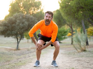 Genç adam elleriyle diz ağrısı kas yaralanması kırık kemik bacak ağrısı burkulma veya kramp çalışan bir egzersiz sırasında yaralanma çalışan açık havada spor eğitim parkında acı sonra holding yerleştirmek.