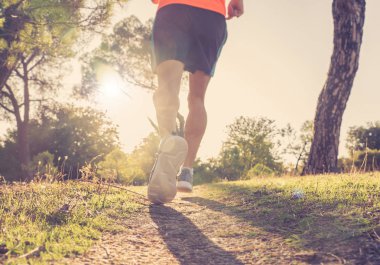 Arkadan görünüşü spor adamla sonbahar günbatımı eğitim koşu kırsal fitness ve sağlıklı yaşam konsepti içinde doğada yoldan çalıştıran atletik ve kaslı bacakları yırtık.