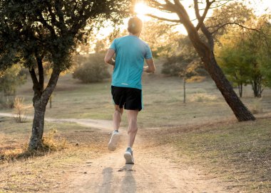Arkadan görünüşü genç dinamik atlet runner adamla uygun güçlü beden eğitimi güzel yaz günbatımı yeşil park çalıştıran ve egzersiz fitness iyi olmak ve sağlıklı yaşam konsepti.