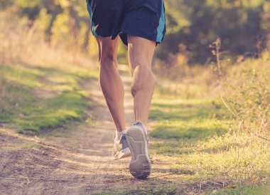 Arkadan görünüşü spor adamla sonbahar günbatımı eğitim koşu kırsal fitness ve sağlıklı yaşam konsepti içinde doğada yoldan çalıştıran atletik ve kaslı bacakları yırtık.