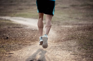 Arkadan görünüşü spor adamla sonbahar günbatımı eğitim koşu kırsal fitness ve sağlıklı yaşam konsepti içinde doğada yoldan çalıştıran atletik ve kaslı bacakları yırtık.