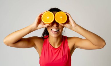 Güzellik tedavi büyük gıda gri arka plan üzerinde izole bir sağlıklı yaşam konsepti için komik çekici neşeli çekici moda modeli kadın holding portakal dilim gözleri yakınındaki gülüyor.
