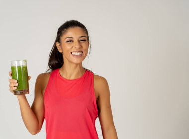 Kadın fitness fitness egzersiz Güzellik Sağlık Fitness diyet beslenme ve sağlıklı yaşam konsepti gri arka plan üzerinde izole çalıştıran sonra holding cam yeşil sebze güler yüzlü gülen mutlu.