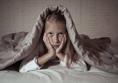 Sevimli küçük beyaz kız duygu yorgun ve uykusuz uykusuzluk depresyon stres çocuklar duygusal ve uyku bozuklukları kavram acı battaniye ile kafasını kapsayan yatakta yalan.
