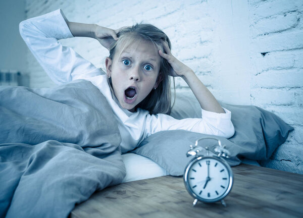 Сладкая бессонная маленькая девочка стресс грустно и сердит в постели глядя на будильник, чтобы проснуться, но чувство бессонницы в бедах оставаться спящим расстройство сна и детей Бессонница концепция
.