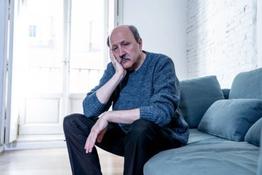 Kıdemli yaşlı adam umutsuz üzgün endişeli bakarak duygu düşünceli ve yalnız evde kanepede yaşlanma zihinsel sağlık kişisel sorunlar ve yaşam tarzı kavramı depresif.