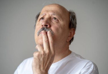 Düşünme ve dalgın Düşünceli yüz insan duyguları ve gri arka plan üzerinde izole yüz ifadesi kavramı ile seyir kıdemli yaşlı adam portresi kapatın.