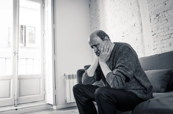 Senior old man feeling desperate sad looking worried depressed thoughtful and lonely on couch at home in Aging Mental health Personal problems and Life style concept.