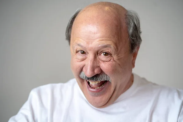 Smiling and laughing 60s year old senior man candid close up portrait in human emotions and facial expressions concept isolated in neutral background.