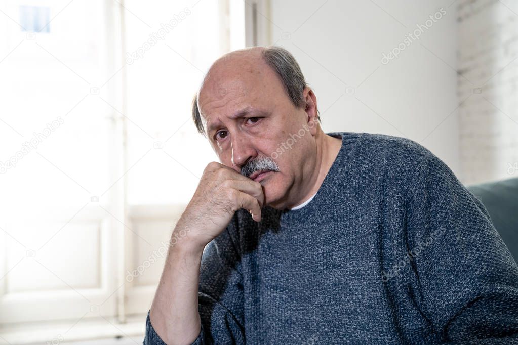 Senior old man feeling desperate sad looking worried depressed thoughtful and lonely on couch at home in Aging Mental health Personal problems and Life style concept.