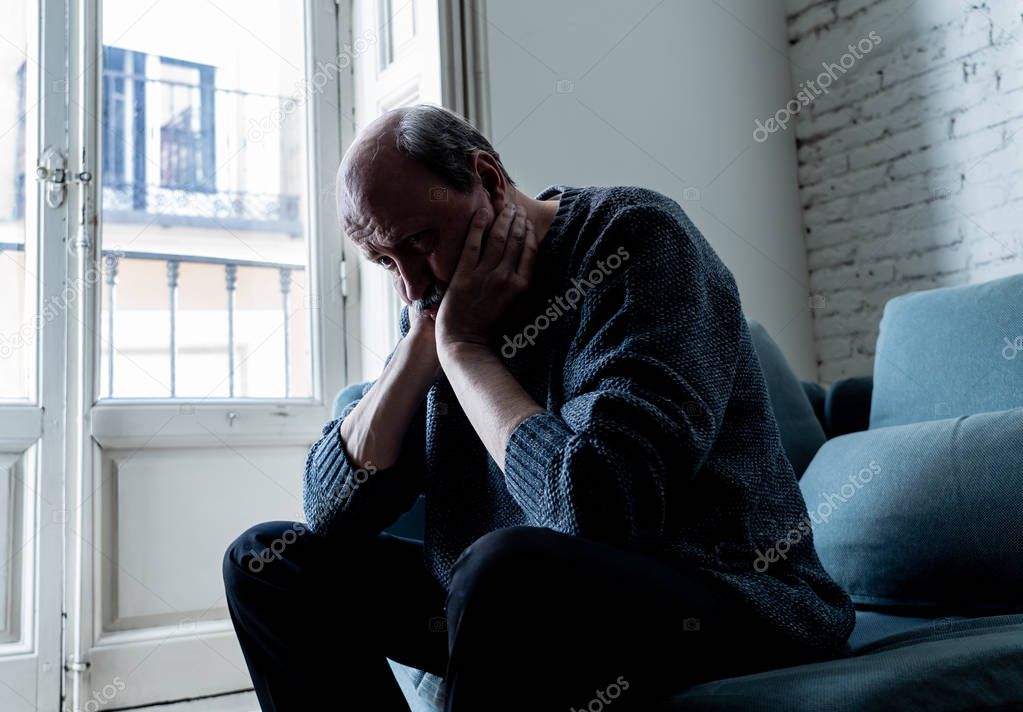 Senior old man feeling desperate sad looking worried depressed thoughtful and lonely on couch at home in Aging Mental health Personal problems and Life style concept.