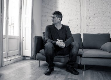 Çekici bir adam duygu umutsuz üzgün endişeli bakarak düşünceli ve yalnız orta yaş krizi ruhsal kişisel sorunlar ve yaşam tarzı kavramı evde kanepede depresyon acı depresif.
