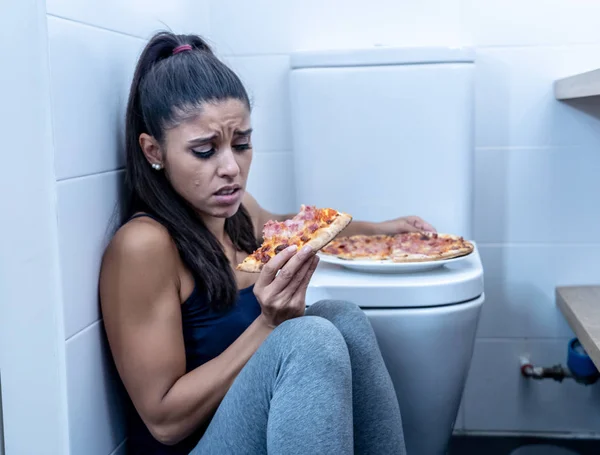 有吸引力的年轻和悲伤的饥饿年轻妇女感到内疚和生病吃 而坐在地板旁边的马桶在饮食紊乱厌食和贪食症概念 — 图库照片
