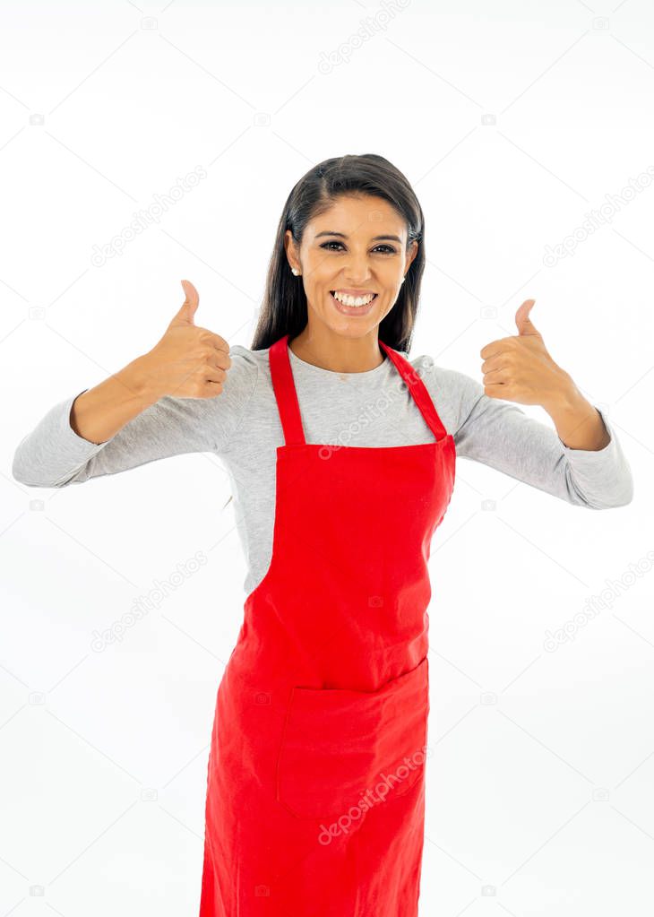 Portrait of a happy proud beautiful latin woman wearing a red apron learning to cook making thumb up gesture in cooking classes small business and homemade spanish food concept isolated on white